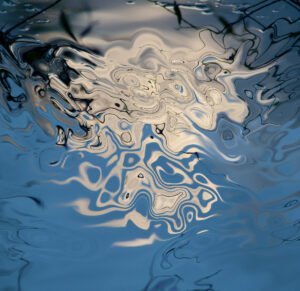abstractions of light on water composed of a floating spot of white light on a fluid blue background with dark shades