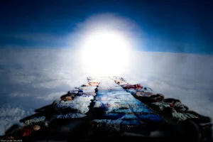 a stone path suspended in the sky above clouds and mountains leads to a circle of light in the sky