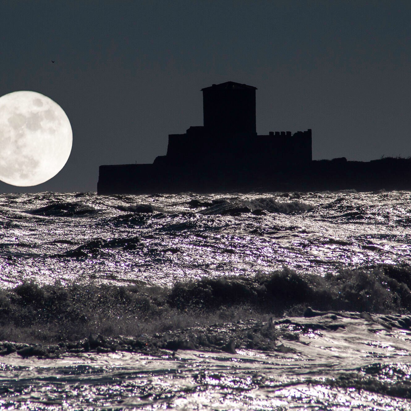 night sea with fortress moon and moonlight reflections on waves